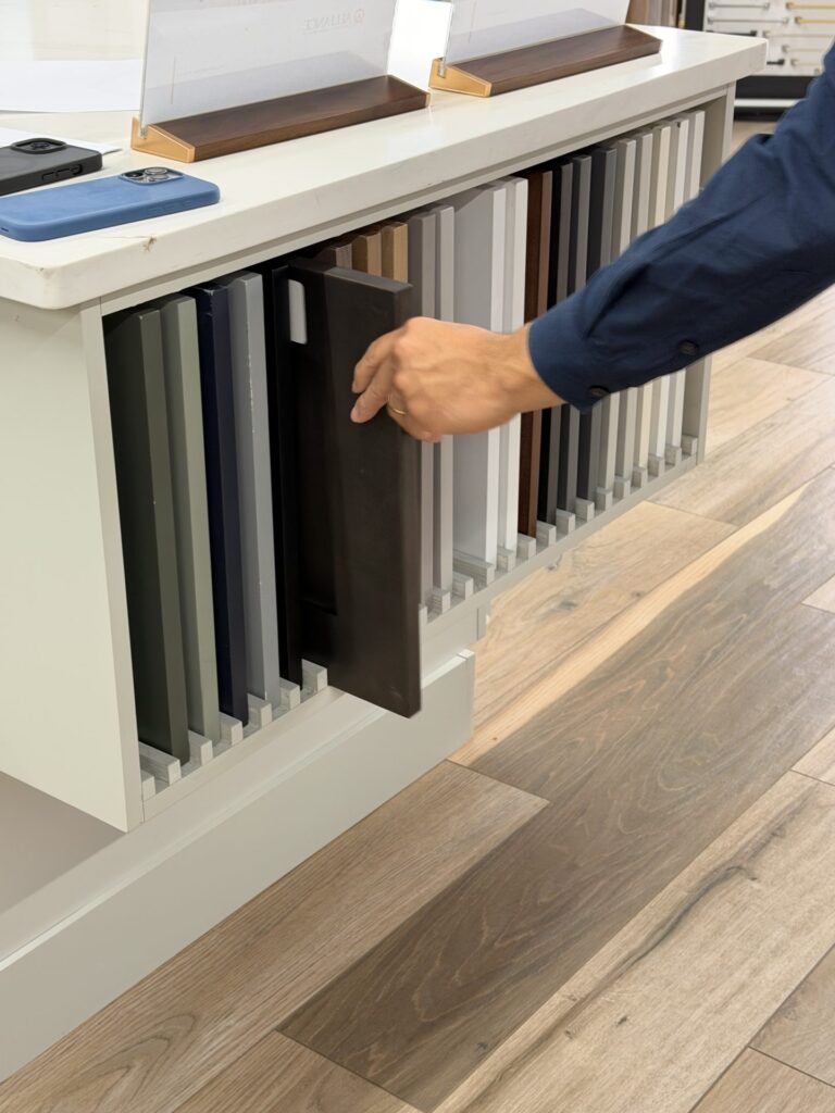 Espresso-stain cabinet door sample pulled from the white display beside painted finishes