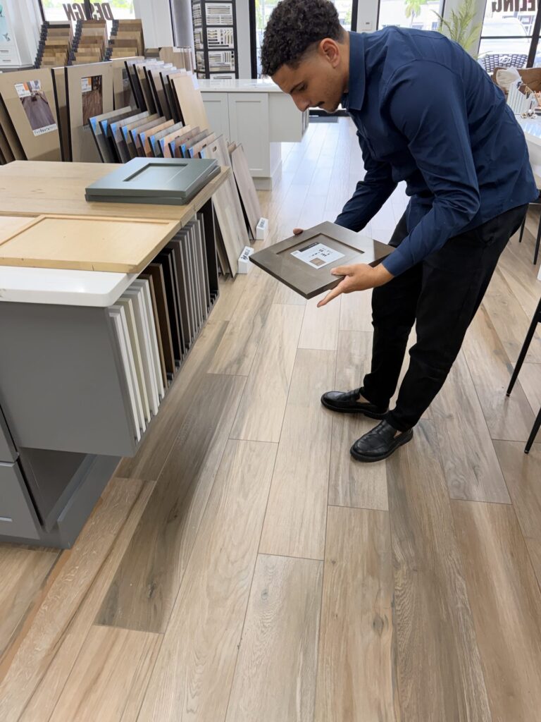 Paulo Lyra, Sales Representative at Alliance Construction, holding a cabinet door sample in the Fort Myers showroom