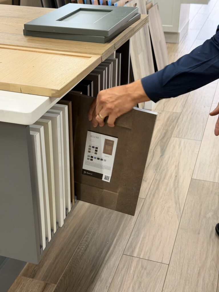 Walnut-tone cabinet door sample with its spec sheet, pulled from the showroom display