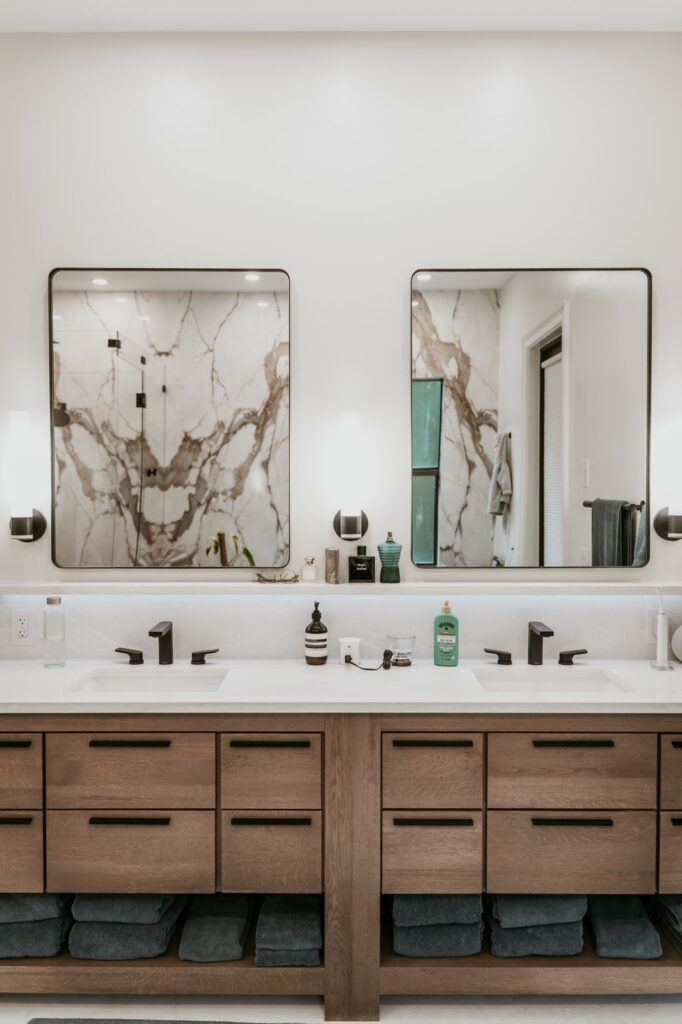 Symmetrical wood double vanity with two mirrors, black faucets, and open lower shelves