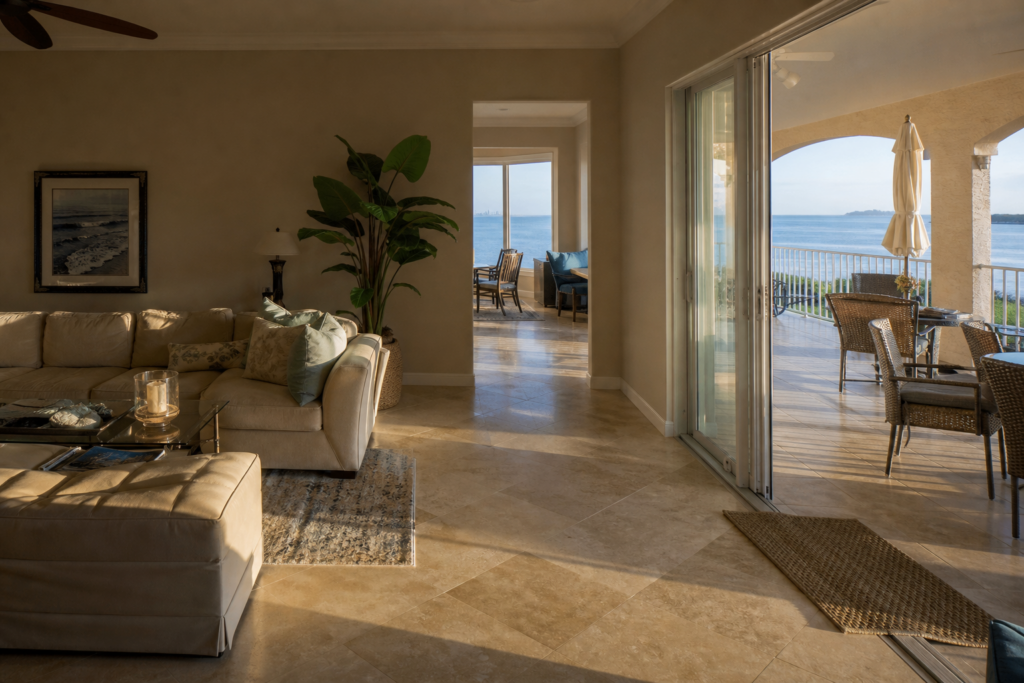 SWFL coastal home interior showing coordinated warm neutral wall color with travertine tile floors and lanai view
