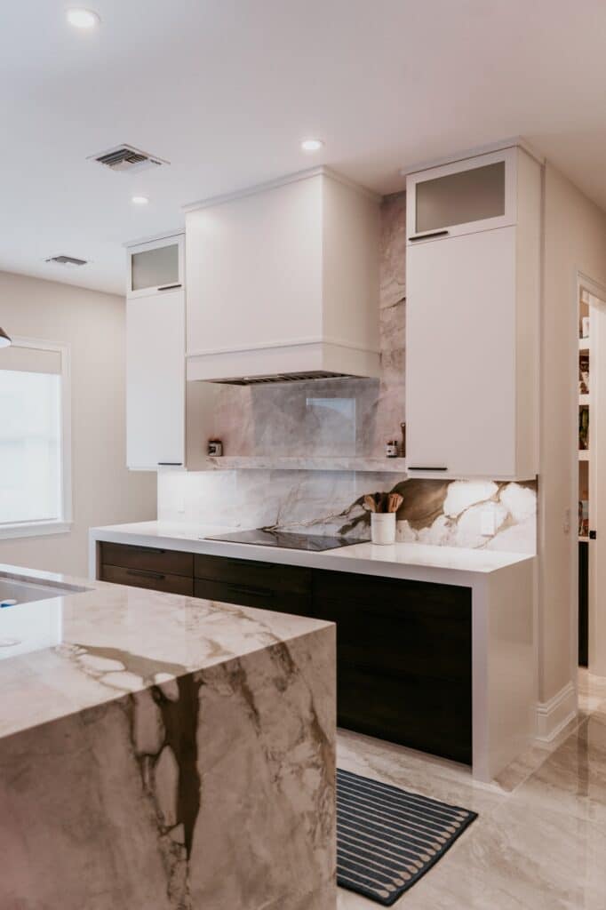 White range hood surrounded by tall cabinets and a veined backsplash