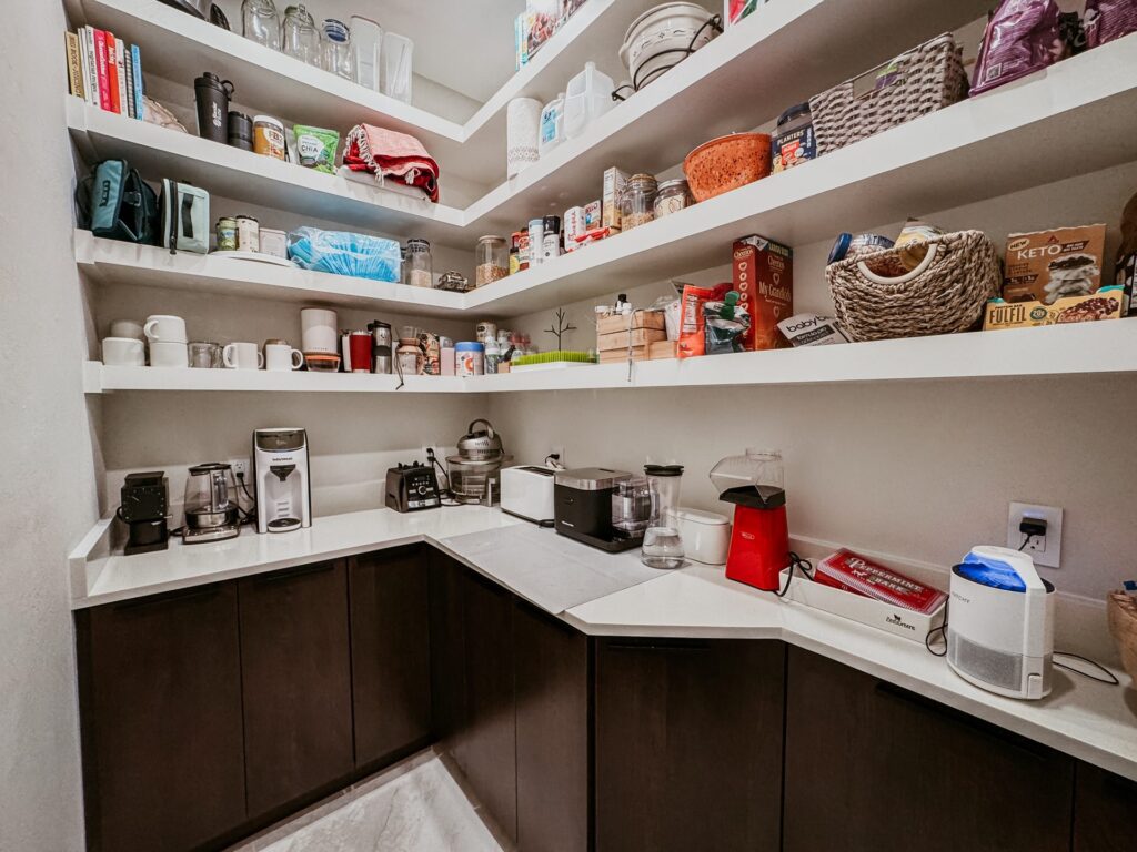 Pantry with open shelves, dark base cabinets, and an L-shaped counter