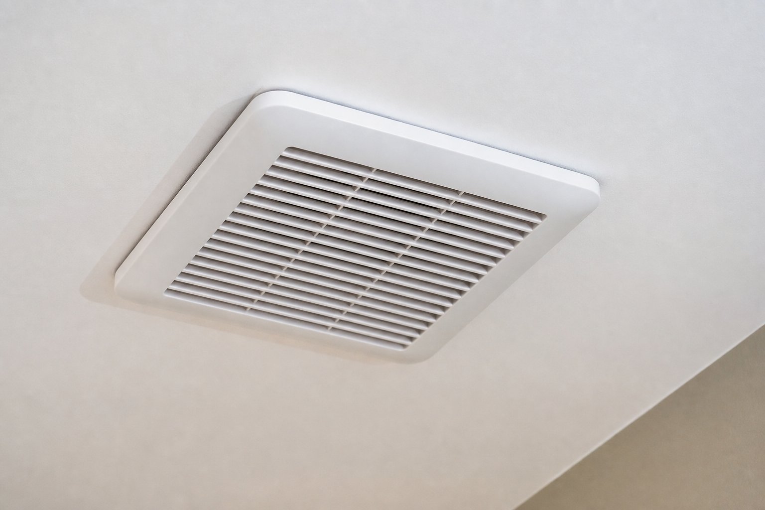 Low profile bathroom exhaust fan grille set flush in a smooth white ceiling