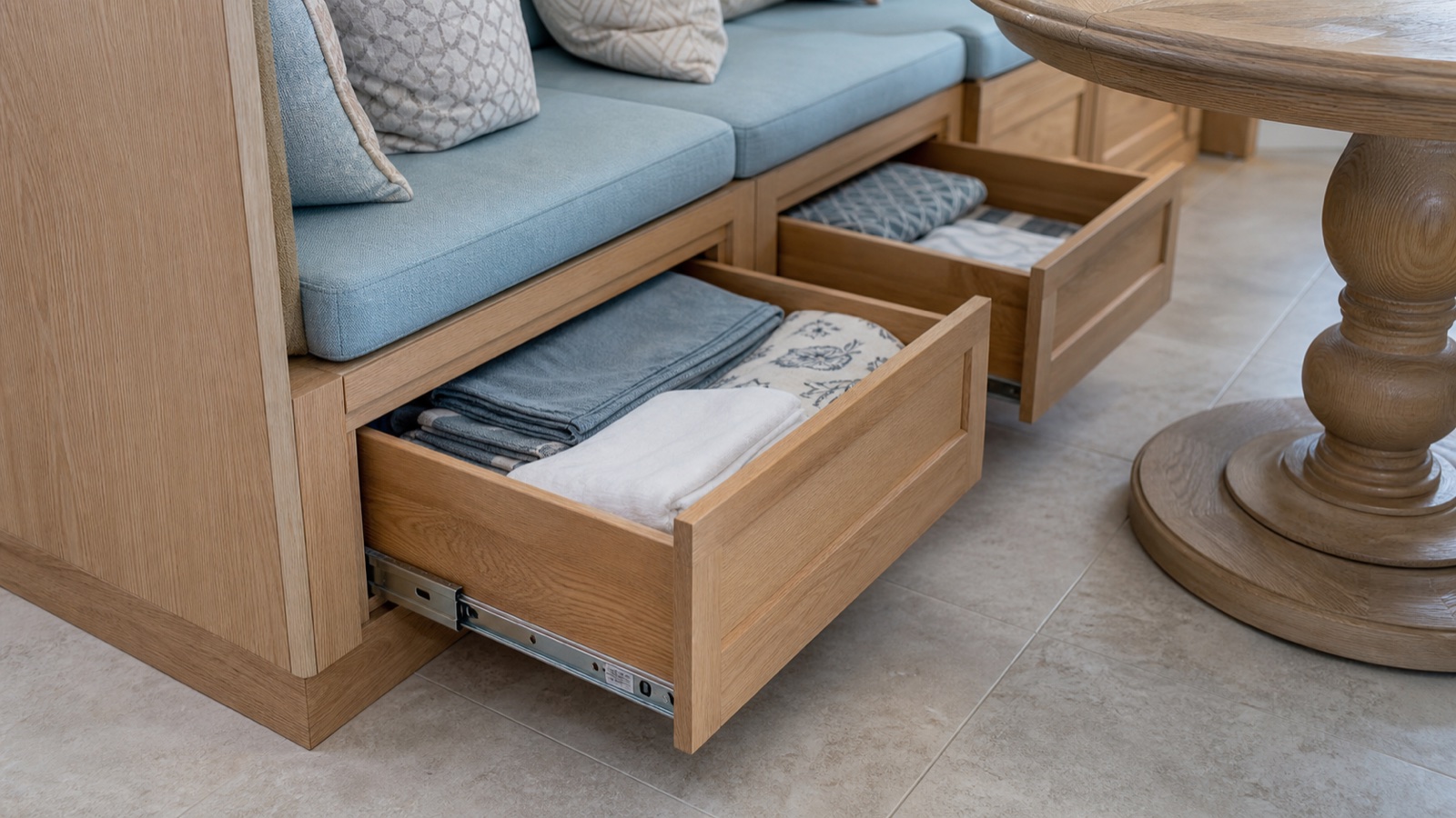 Wide storage drawers beneath a cushioned white oak breakfast banquette
