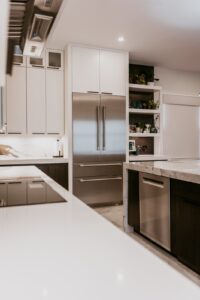Wide view of the kitchen with panel-ready fridge, mixed white and dark cabinetry and waterfall counters.