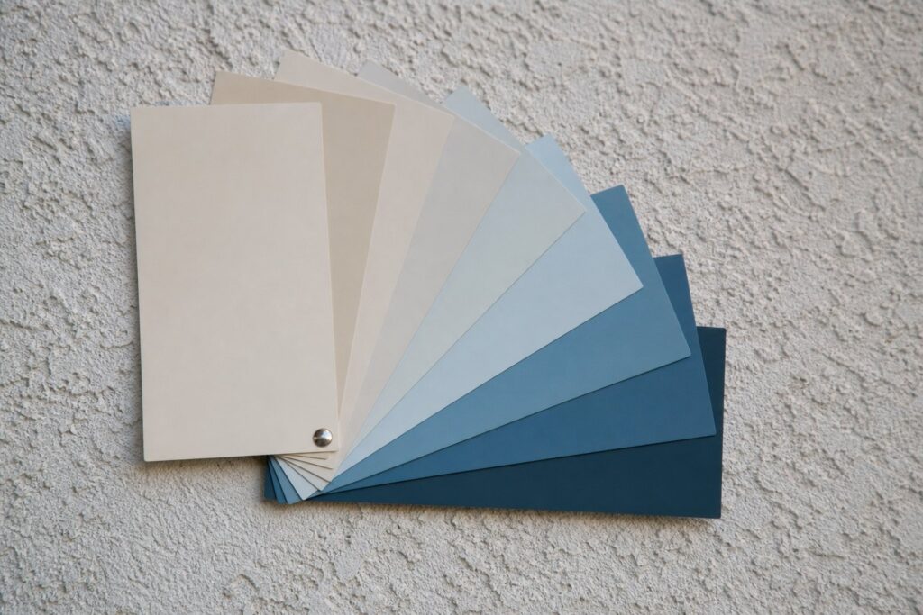 Exterior paint color swatches against a stucco wall