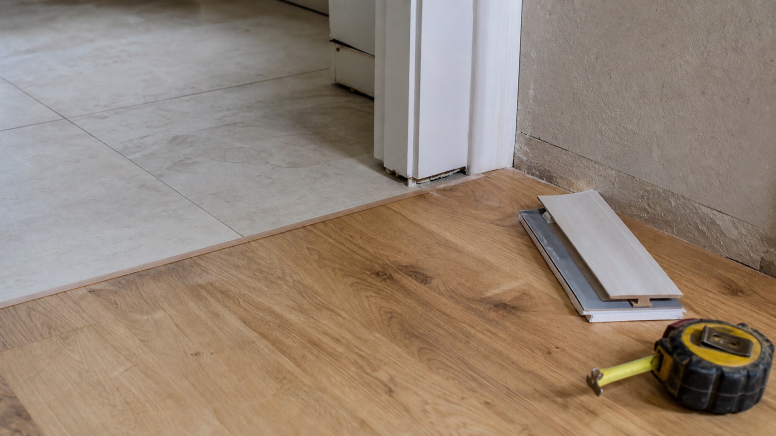 Slim reducer joining porcelain tile and engineered wood at an interior doorway
