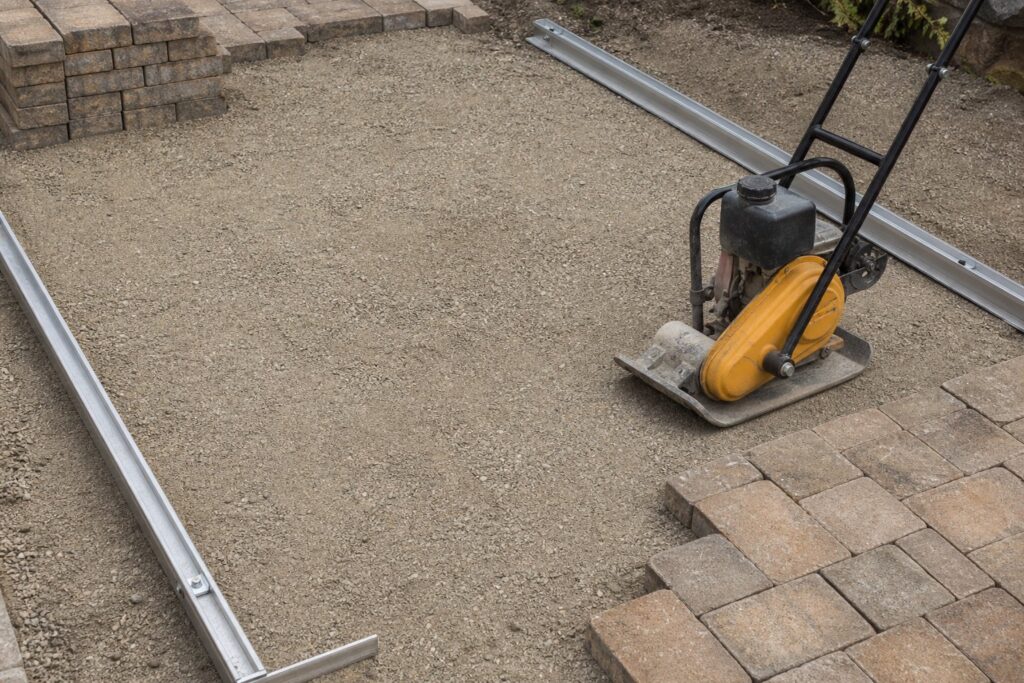 Compacted crushed stone and sand base being prepared for pavers