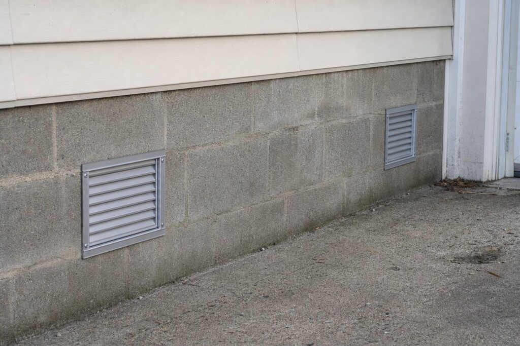Louvered openings set into a lower concrete block foundation wall