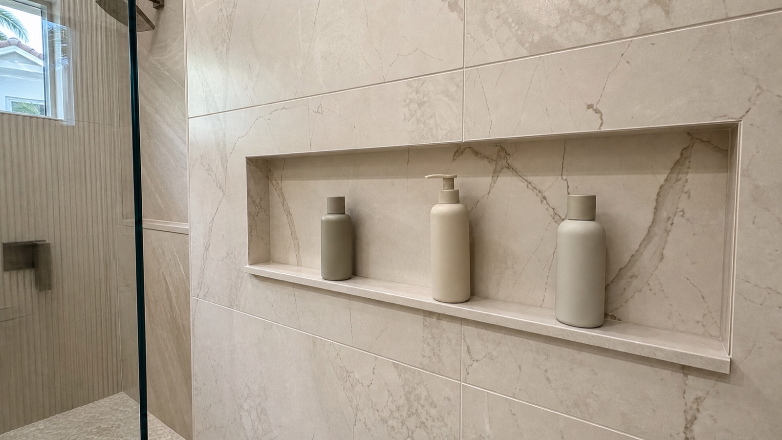 Wide shower niche aligned with porcelain wall-panel veining and grout joints