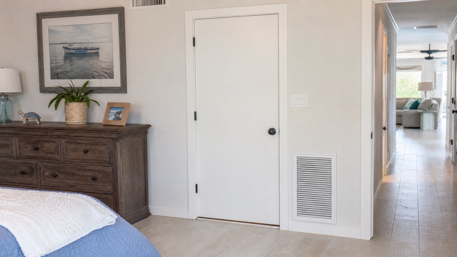 Interior bedroom door with an apparent undercut, upper vent, lower grille, and nearby wall switch