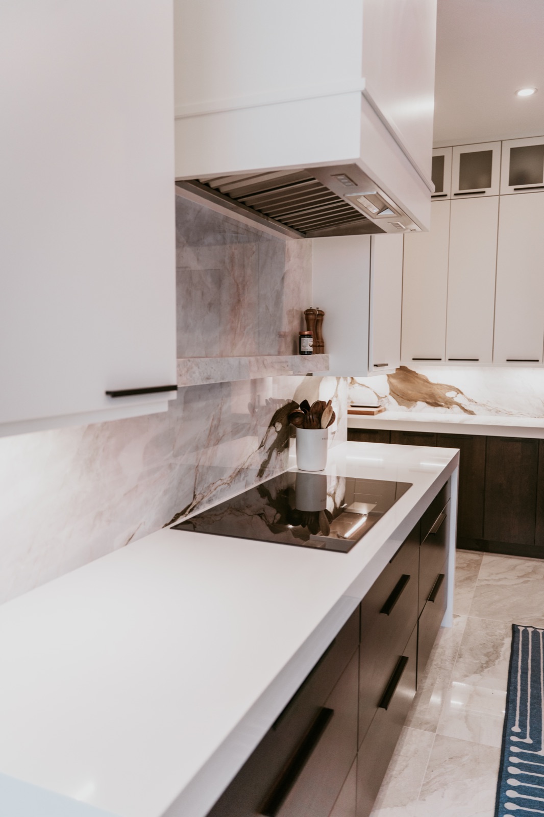 Clean white countertop edge below an induction cooktop and marble backsplash