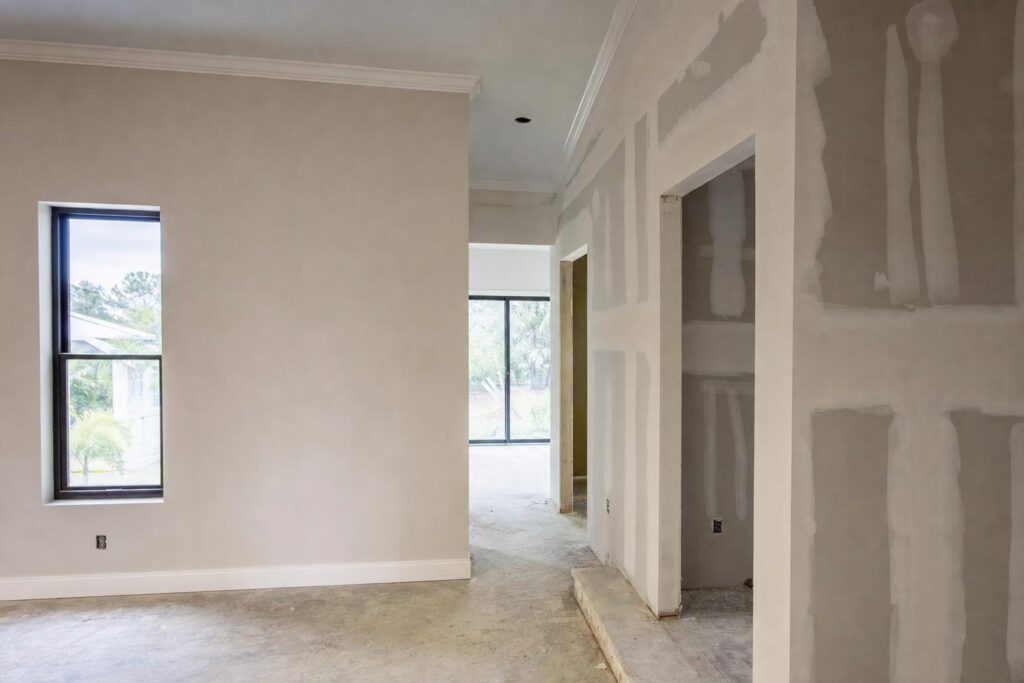 Finished smooth drywall beside taped unfinished drywall in a Fort Myers remodel