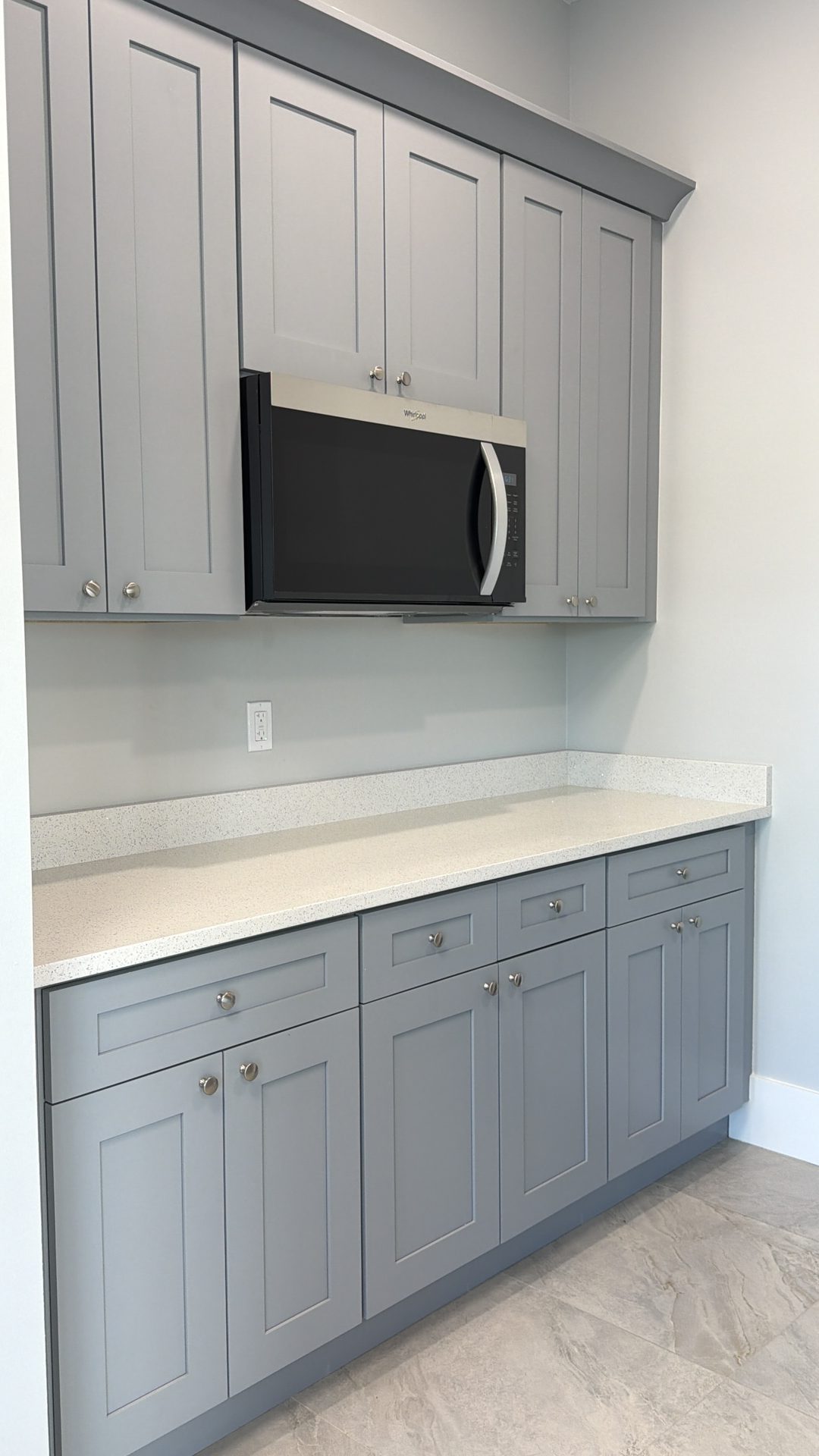 Gray shaker kitchenette wall with microwave nook and white quartz counter built by Alliance Construction in Fort Myers