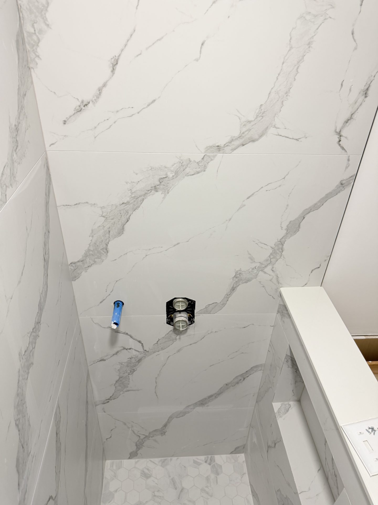 Walk in shower with large format marble look porcelain slab walls and valve rough in during a Fort Myers bathroom remodel