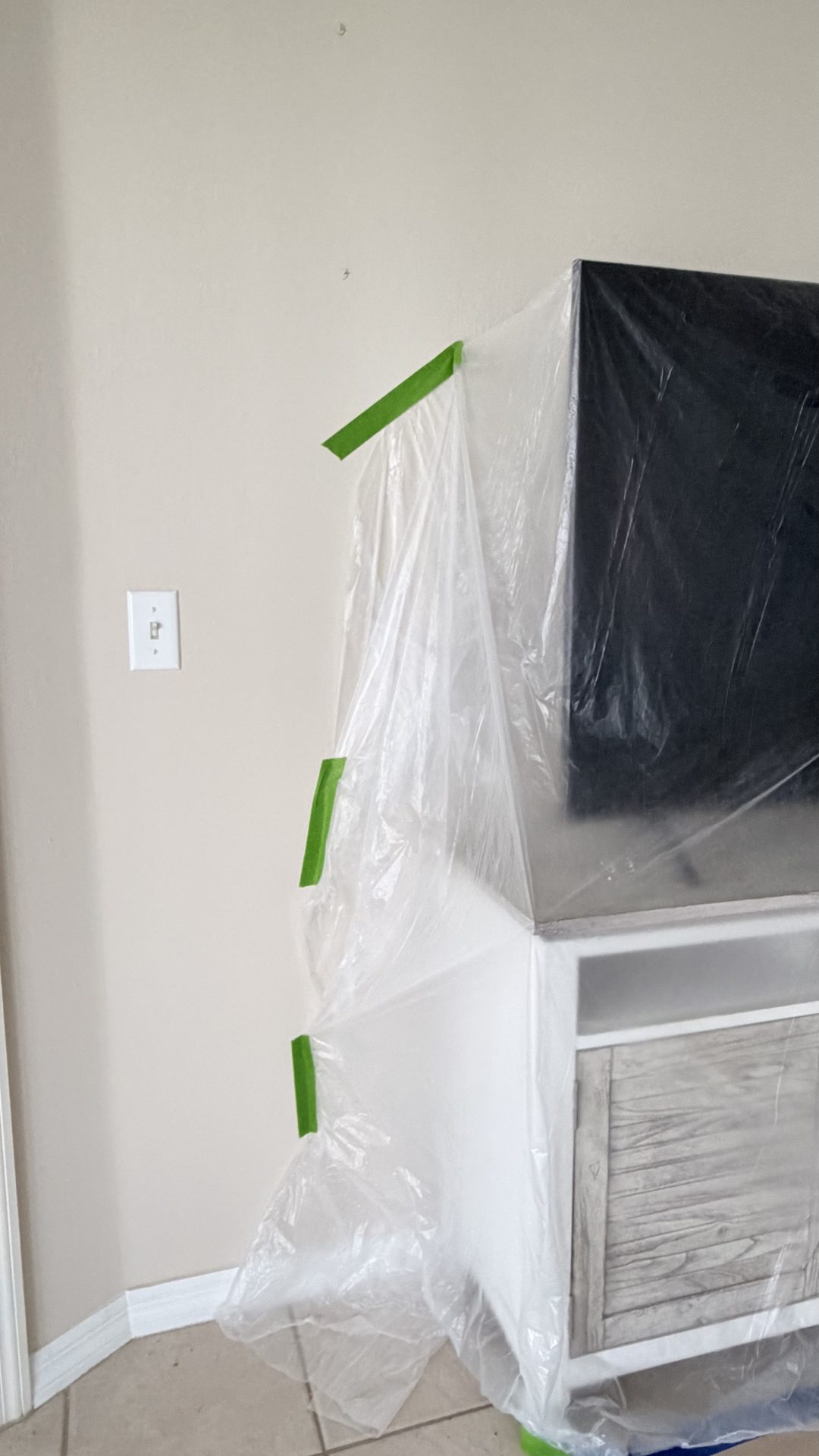 Furniture wrapped in protective plastic sheeting inside an occupied Fort Myers home during remodeling