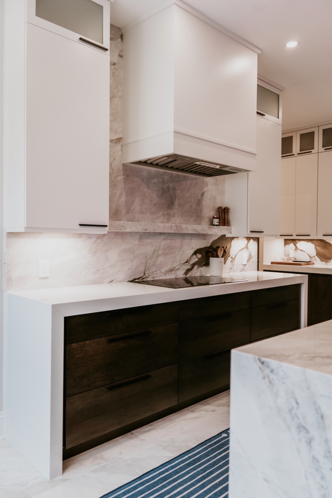 Dark drawer pulls below a cooktop and marble backsplash