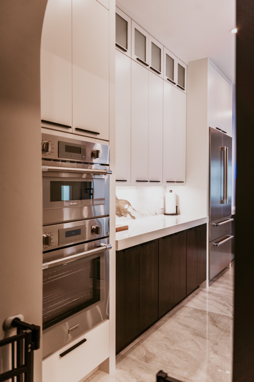 Mixed white and dark cabinets with coordinated handles around wall ovens