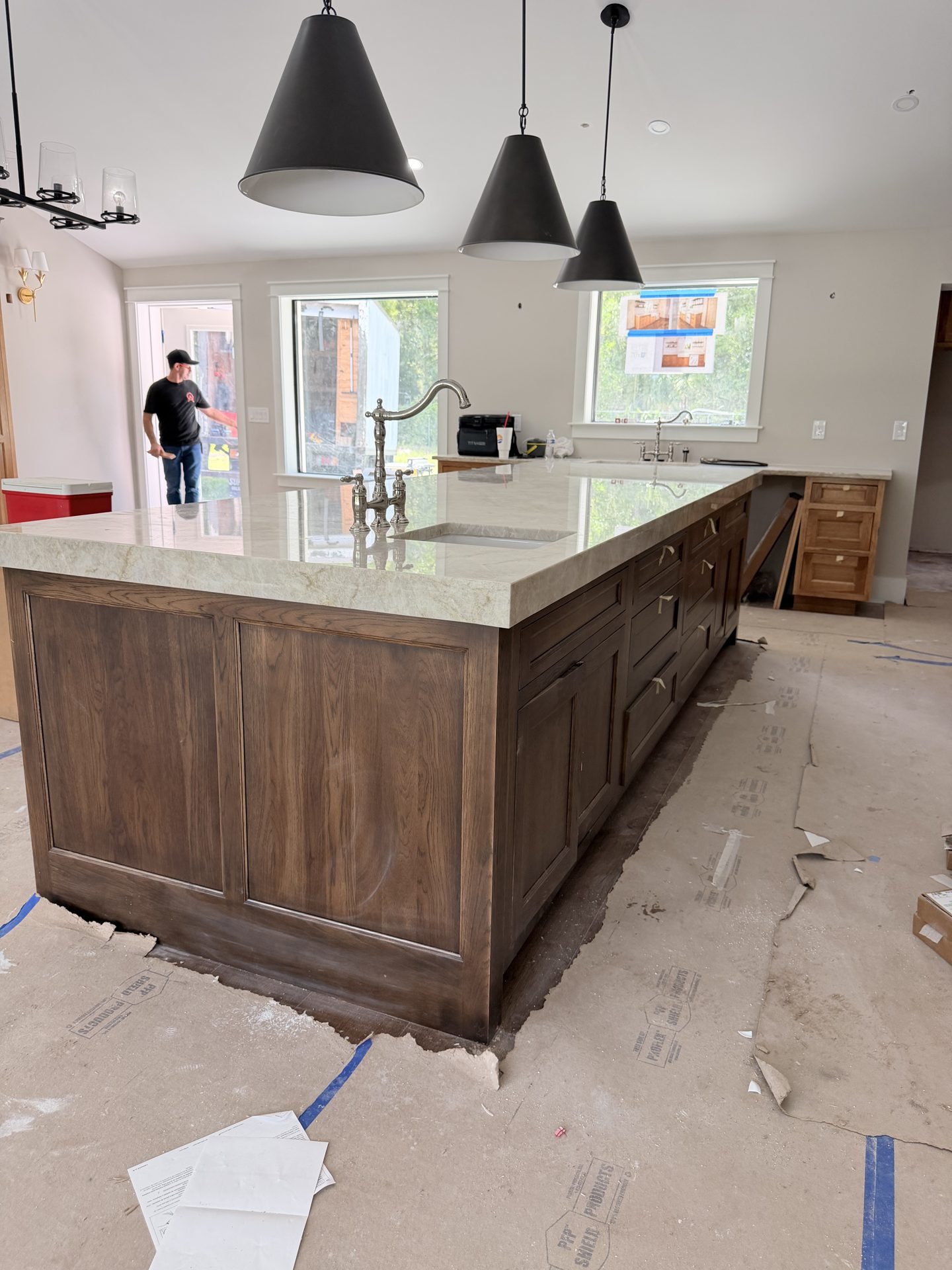 Custom stained oak kitchen island with Taj Mahal quartzite countertop and polished nickel bridge faucet in Fort Myers