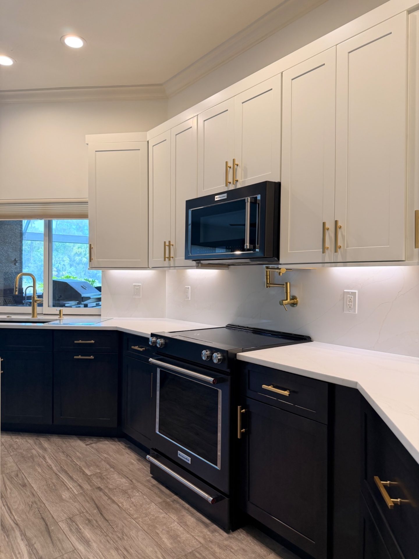 KitchenAid black stainless range with brass pot filler and quartz slab backsplash in a two tone kitchen remodel