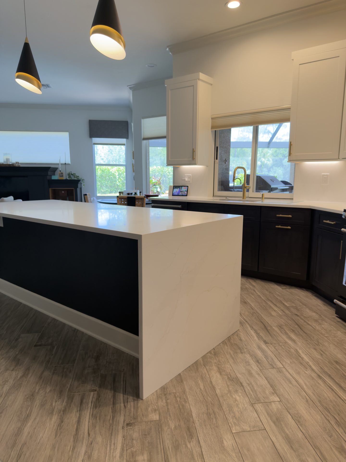 White quartz waterfall island with the kitchen window and backyard view beyond