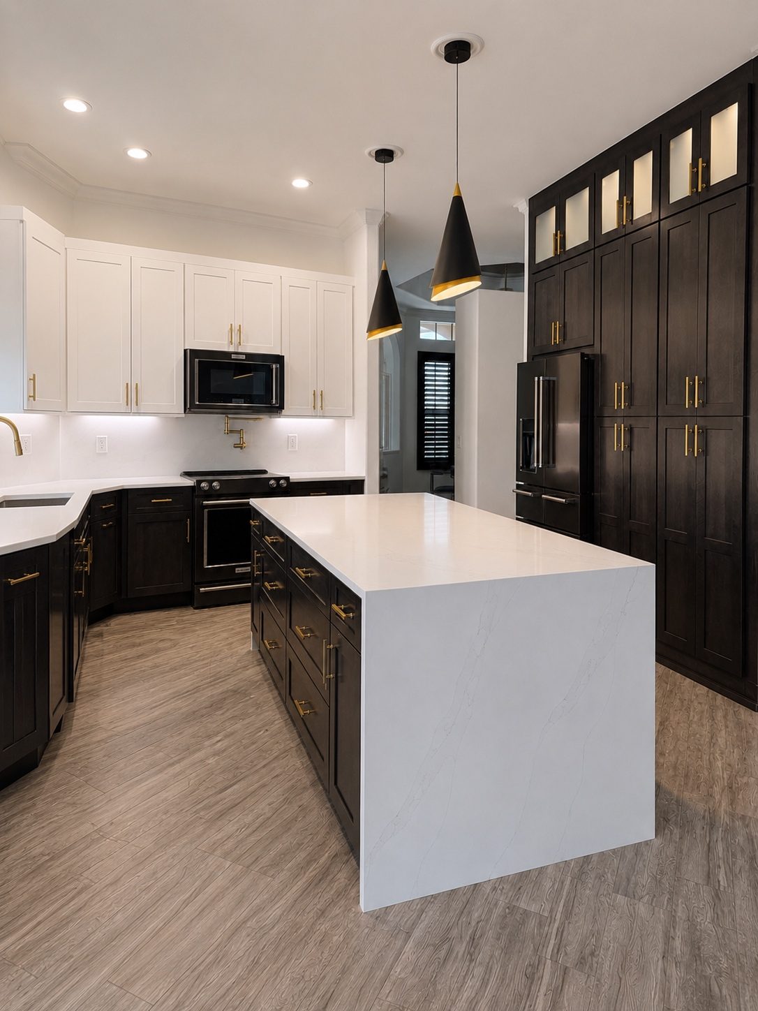 Two tone kitchen with white quartz waterfall island, espresso pantry wall and black cone pendants