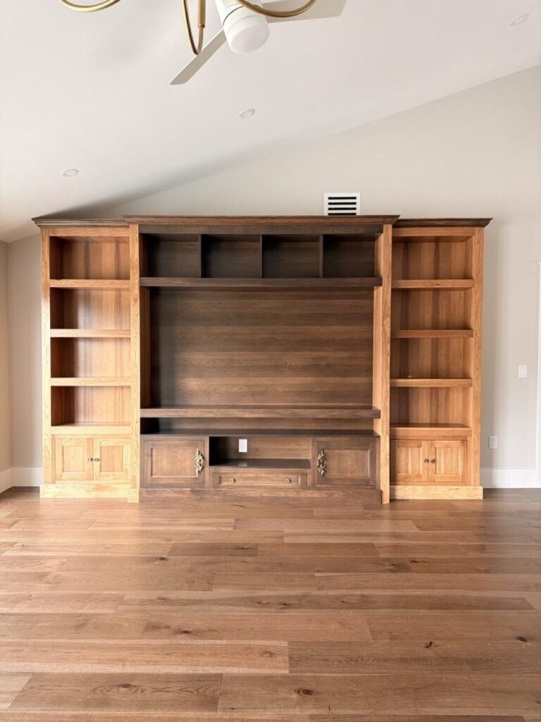 Full wall stained wood built-in entertainment center with open shelving and closed cabinets in a remodeled Fort Myers living room