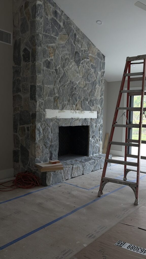 Stacked stone fireplace during the final stage of a Fort Myers whole home remodel, with a ladder and floor protection in place
