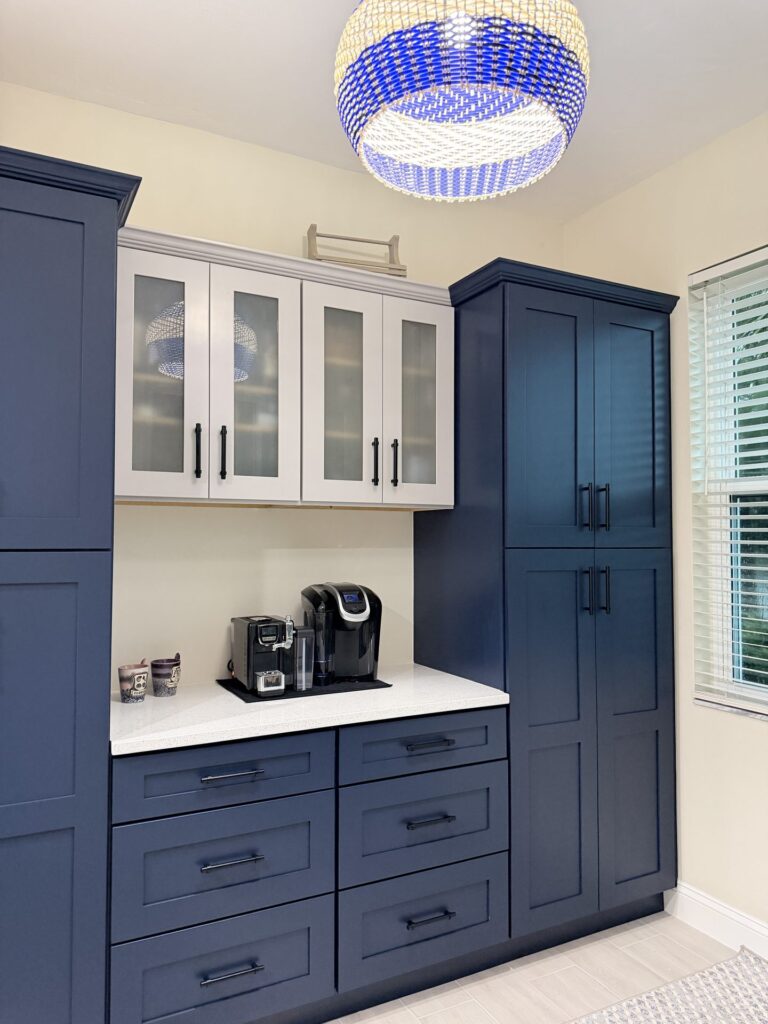 Coffee bar with frosted glass front upper cabinets between two full height navy pantry towers and a navy drawer bank
