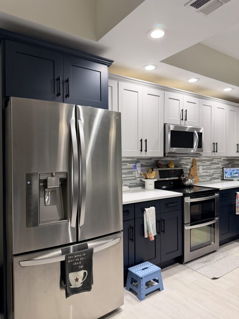 Stainless refrigerator framed by navy shaker cabinets, with the range wall beyond