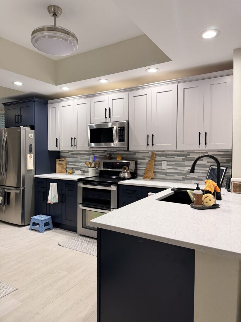 Remodeled Fort Myers kitchen with light gray shaker upper cabinets, navy shaker lower cabinets and a white island counter