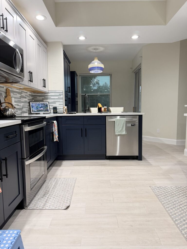 Low view of navy base cabinets along the kitchen window wall with a light plank tile floor